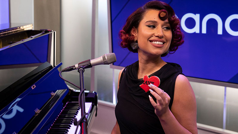 Raye at SiriusXM Studios sitting at a piano, in front of a mic